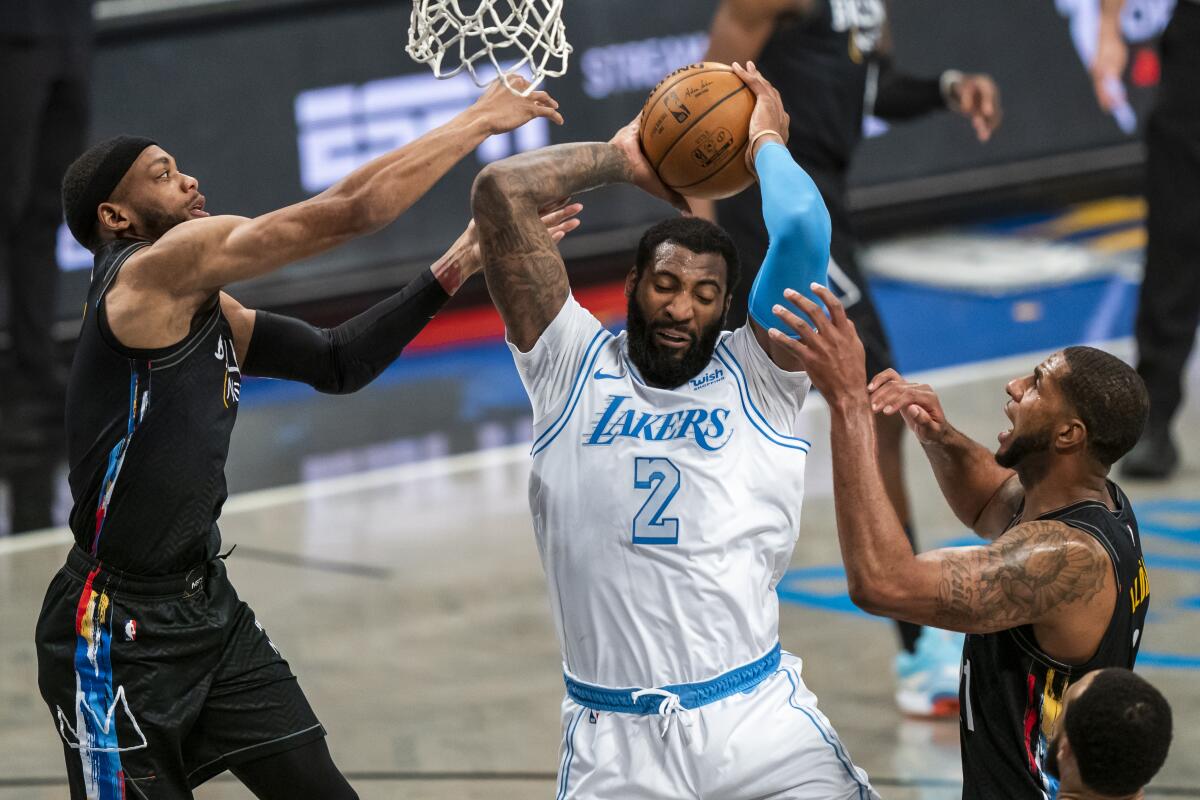 Los Angeles Lakers center Andre Drummond (2) grabs a rebound between Brooklyn Nets forward Bruce Brown, left, and center LaMarcus Aldridge during the first half of an NBA basketball game Saturday, April 10, 2021, in New York. (AP Photo/Corey Sipkin)