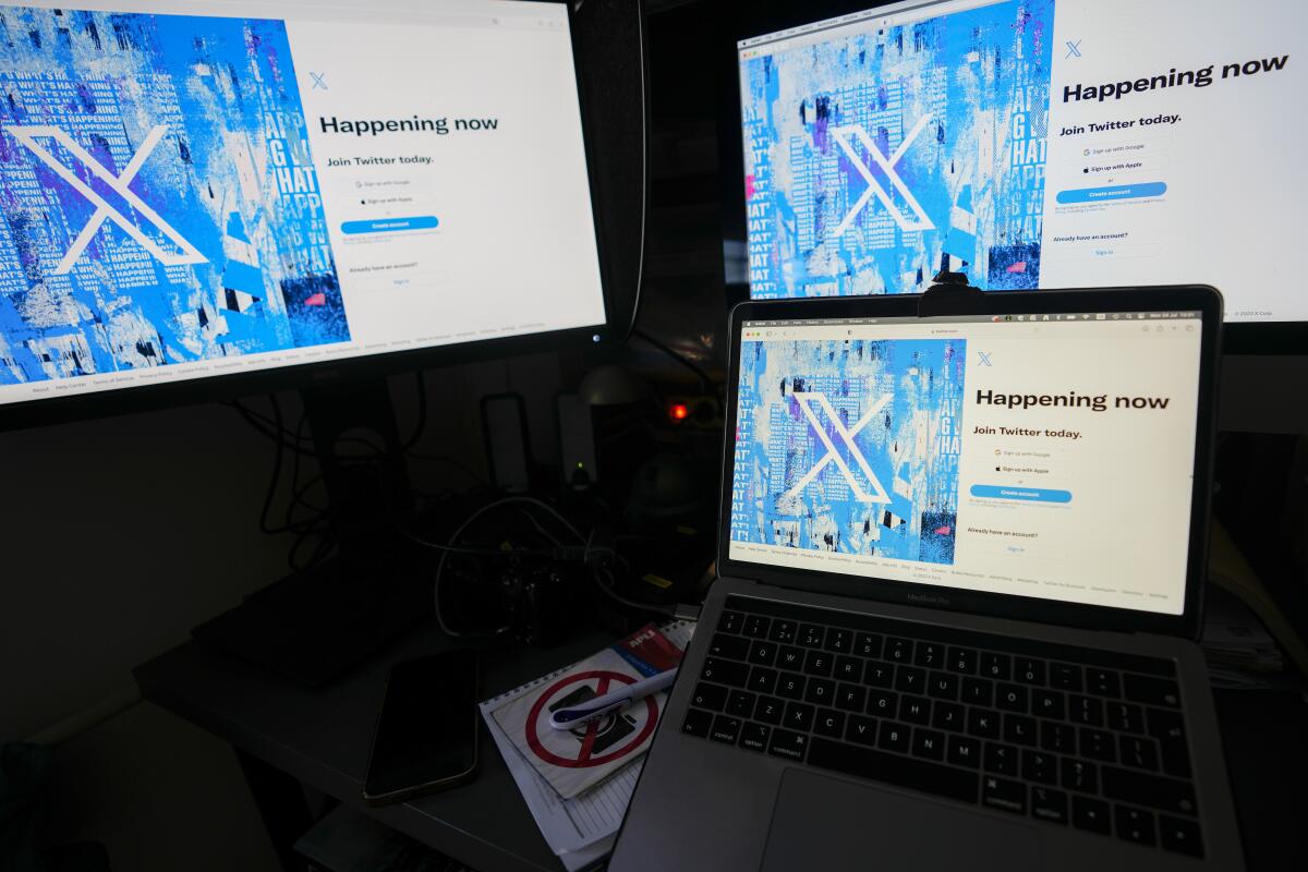 ARCHIVO - Monitores de computadoras y una laptop muestran la página de inicio de sesión de X