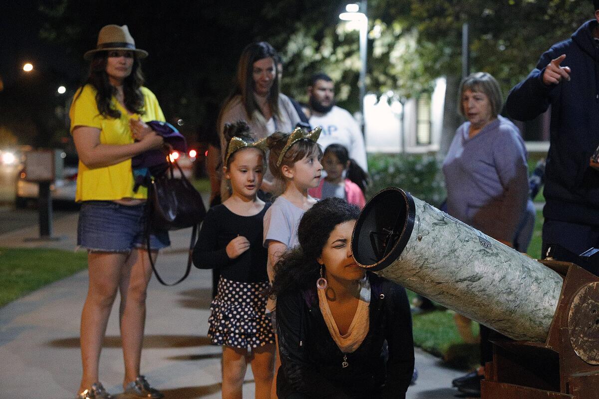 Caroline Bentes, of Burbank, takes a look at Saturn at a "Moon Watch" viewing event hosted by Sidewalk Astronomers at the Buena Vista Branch Library in Burbank on Tuesday. The group will return to library on December 3.
