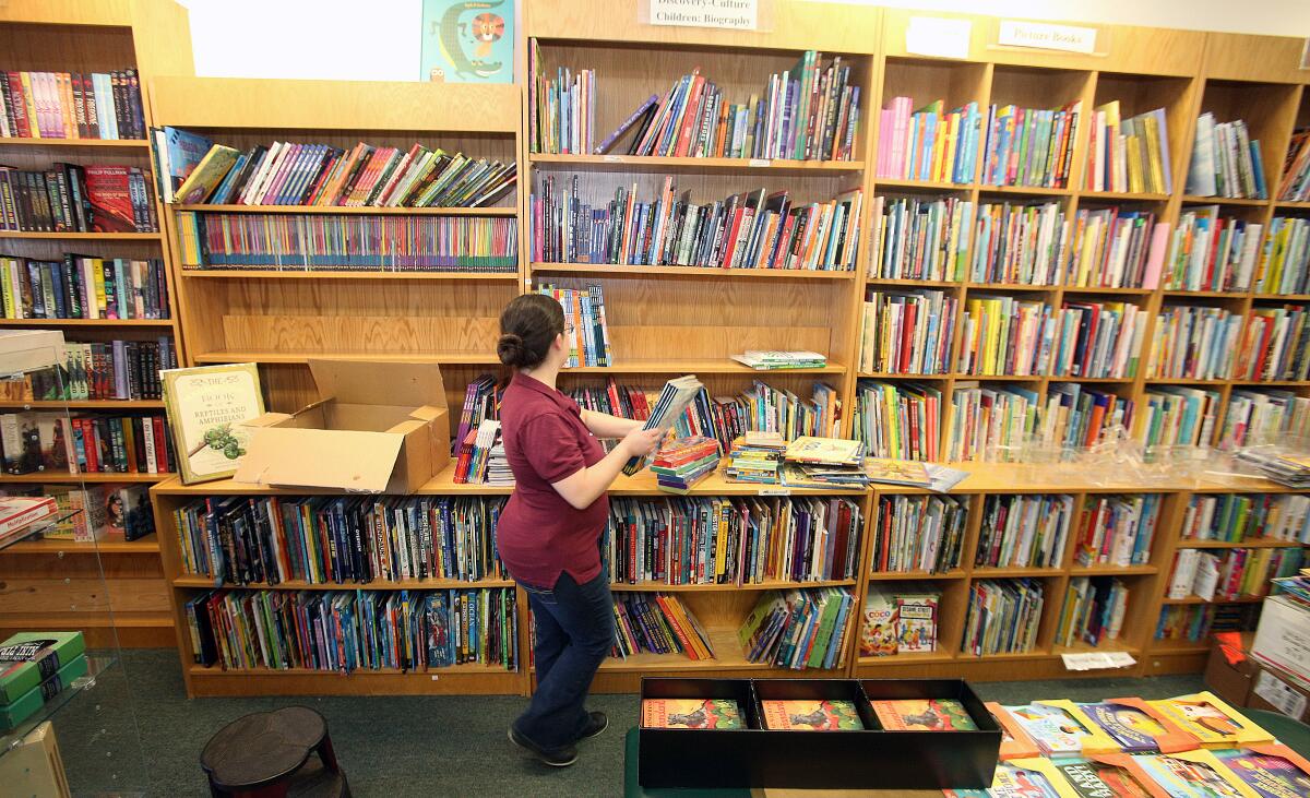Employee Annie Welch, of Sunland, who has worked at the store for three years, organizes children's book titles in the new location of the Flintridge Bookstore Tuesday in La Cañada Flintridge.