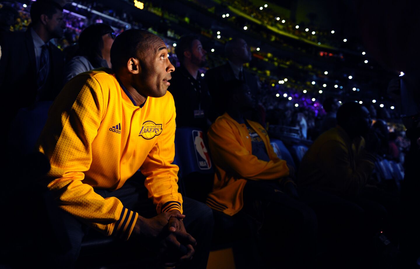 A spotlight shines on Kobe Bryant in a darkened Staples Center as a video tribute to him plays before the last game of his career.