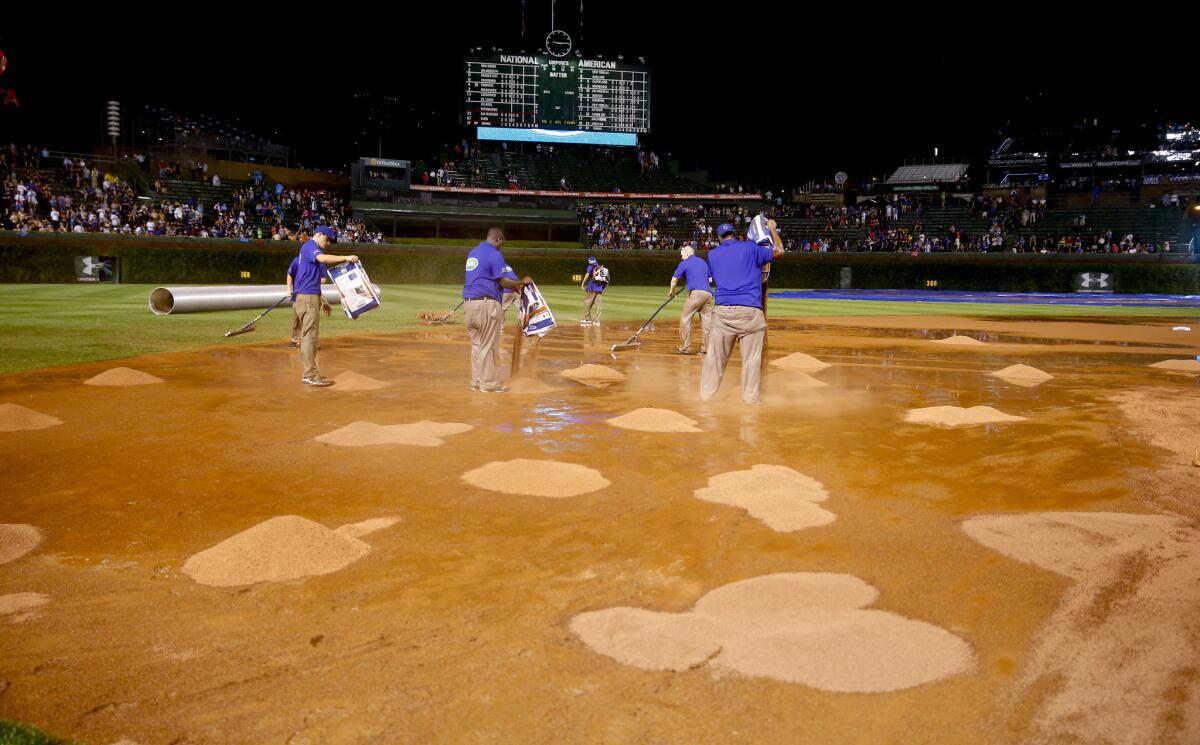 The grounds crew works on the field after a heavy rain soaked Wrigley Field during the fifth inning Tuesday.