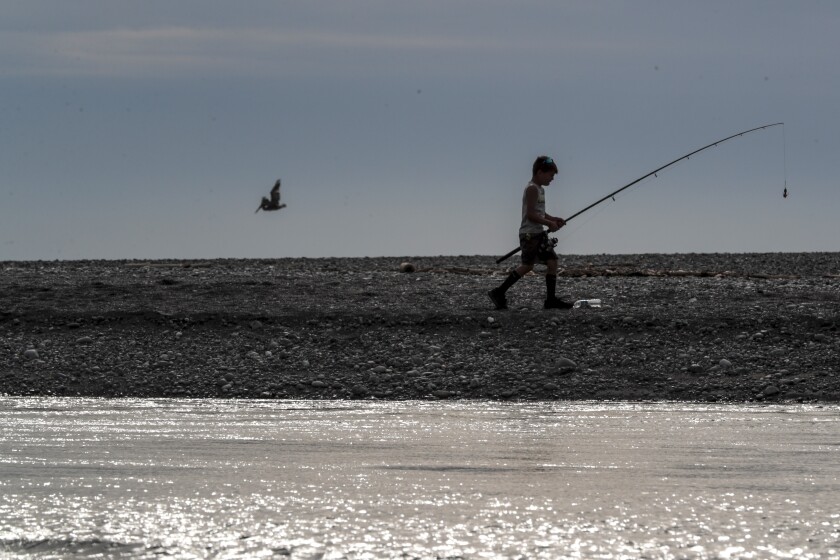 Klamath, CA, Thursday, June 10, 2021 - A young fisherman walks along a spit of land separating the Pacific Ocean and the Klamath River. (Robert Gauthier/Los Angeles Times)