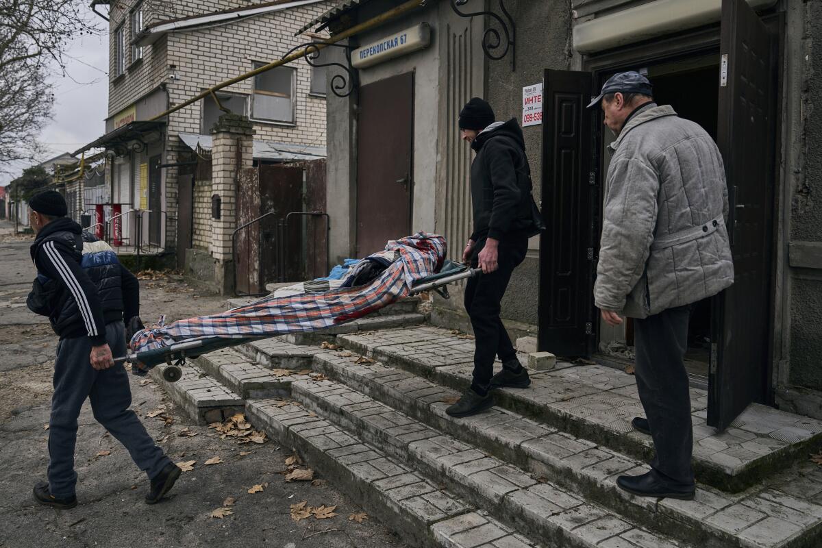 People carrying away the body of a man on a stretcher in Kherson, Ukraine