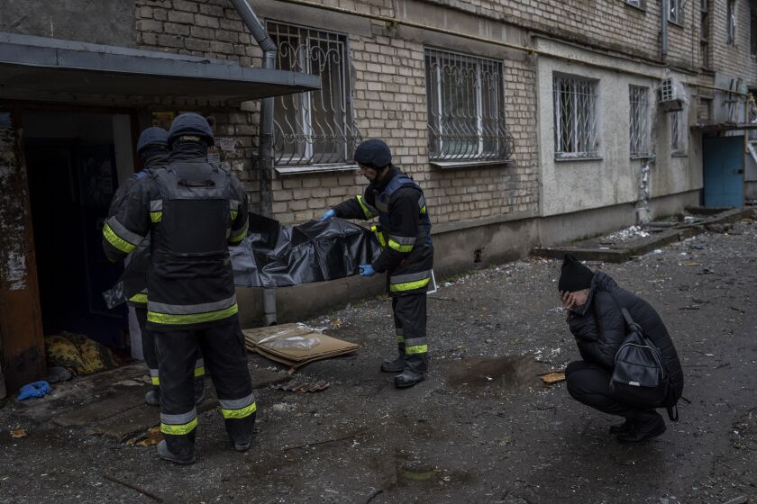 Lilia Kristenko, 38, cries as city responders collect the dead body of her mother Natalia Kristenko in Kherson, southern Ukraine, Friday, Nov. 25, 2022. Natalia Kristenko's dead body lay covered in a blanket in the doorway of her apartment building for hours overnight. The 62-year-old woman had walked outside her home with her husband Thursday evening after drinking tea when the building was struck. Kristenko was killed instantly from a wound to the head. Her husband died hours later in the hospital from internal bleeding. (AP Photo/Bernat Armangue)