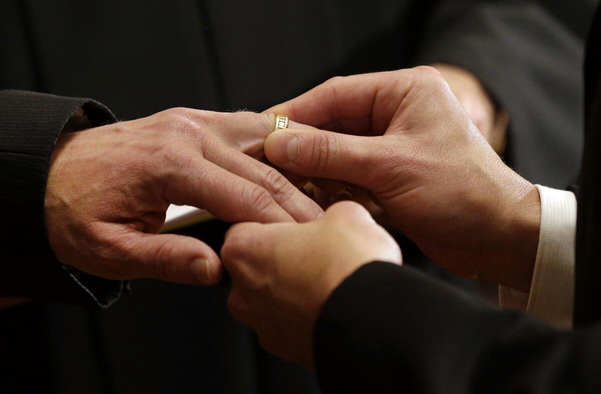 Thomas Rabe, right, places a wedding ring on Robert Coffman's finger during a marriage ceremony at City Hall in Baltimore, Md., where same-sex couples are now legally permitted to marry.