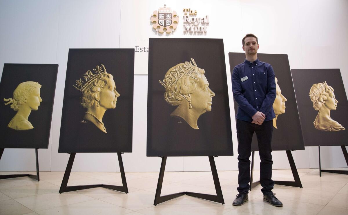 Mint engraver Jody Clark stands with the coin portrait he created of Queen Elizabeth II. Displayed are four previous coin portraits of the queen.
