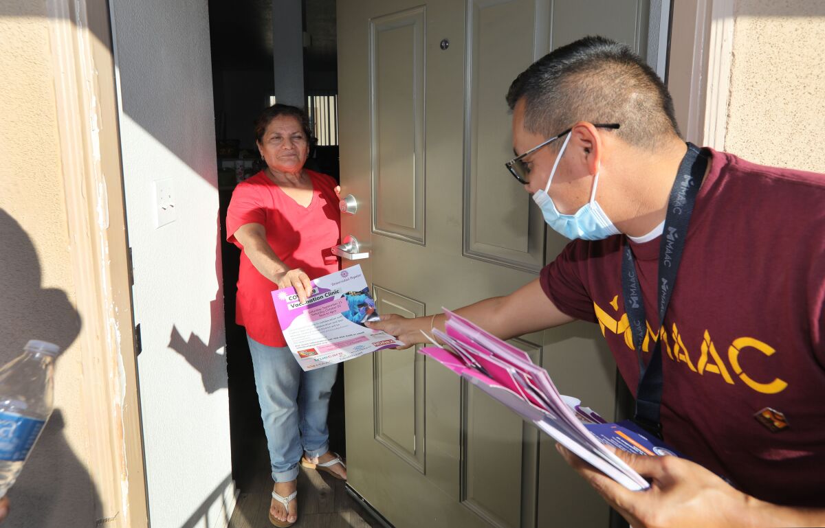 Octaviana Arango receives a flyer about a vaccine clinic at San Marcos Elementary from volunteer Rafael Lopez 