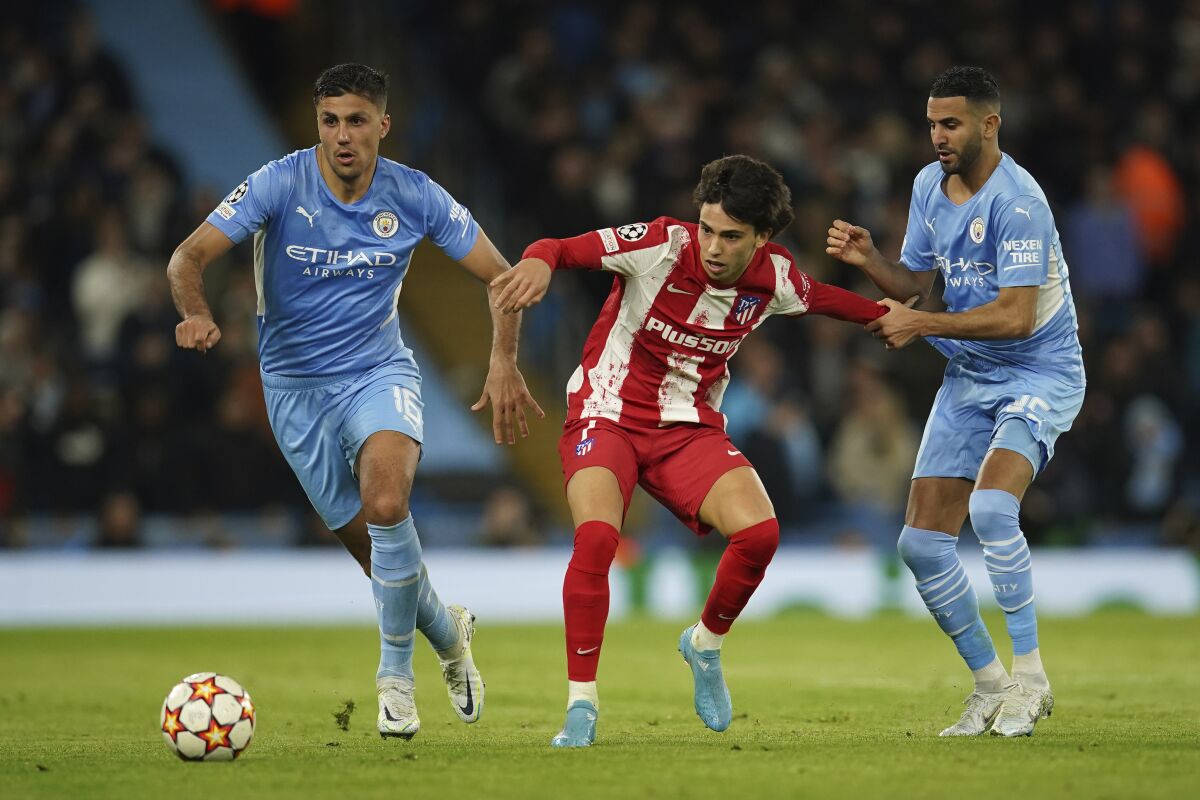 Atletico Madrid's Joao Felix, center, is challenged by Manchester City's Rodrigo, left, and Manchester City's Riyad Mahrez during the Champions League, first leg, quarterfinal soccer match between Manchester City and Atletico Madrid at the Etihad Stadium, in Manchester, Tuesday, April 5, 2022. (AP Photo/Dave Thompson)