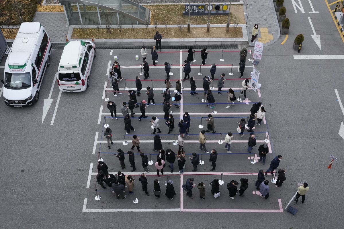 People stand in a parking lot in areas marked off by white painted lines
