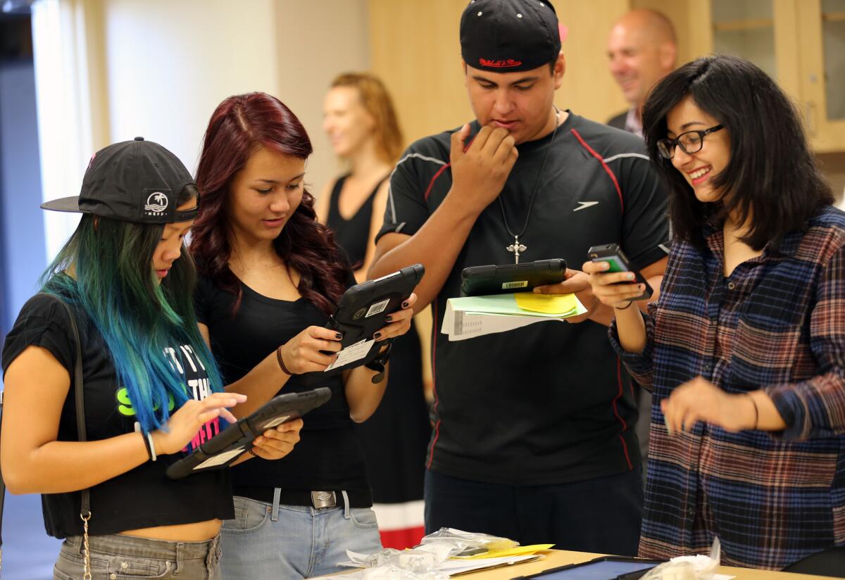 Valley Academy of Arts and Sciences students, from left, Jordann Ventura, 14, Karyna Mills, 15, Guillermo Romero, 15, and Dayanara Trujillo, 15, receive iPads before the start of the school year.