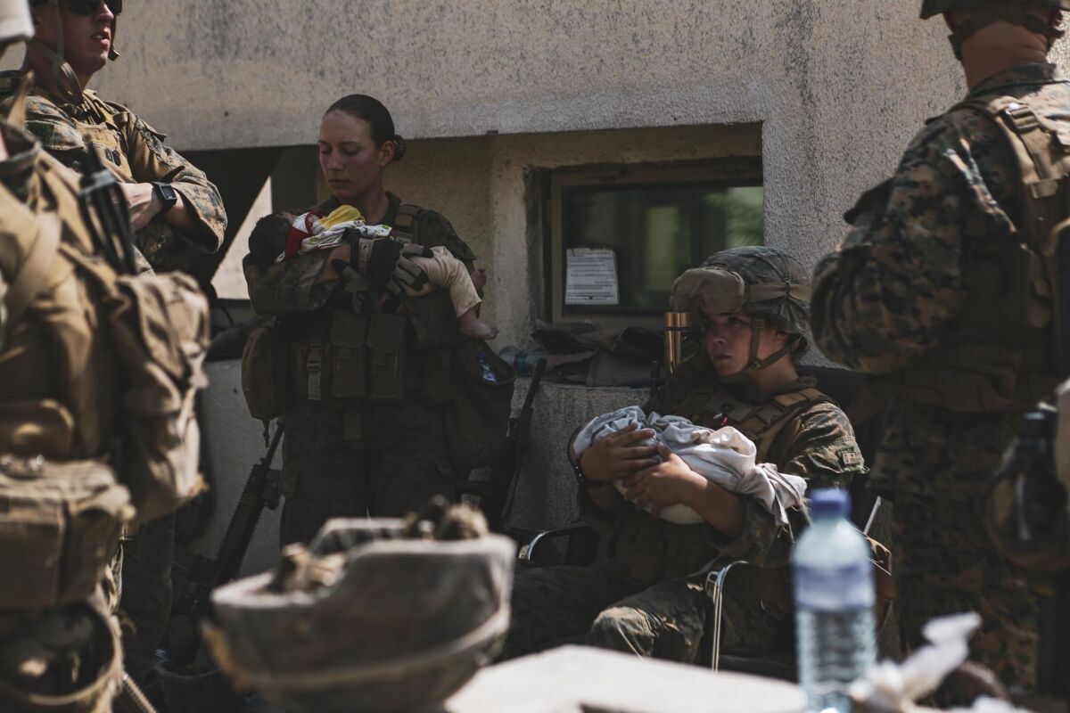 Marine Sgt. Nicole Gee stands with an Afghan baby while surrounded by other U.S. military members