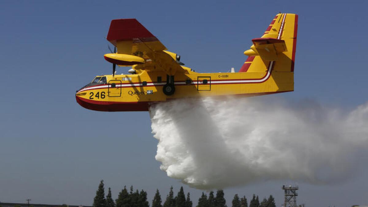 A super scooper dumps water on the grass near the Van Nuys airport in 2014.