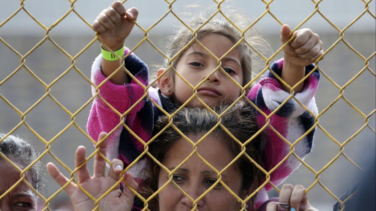 A six-year-old sits on the shoulders of her mother as they look out through the fence of a immigrant shelter in Piedras Negras, Mexico on Feb. 5.