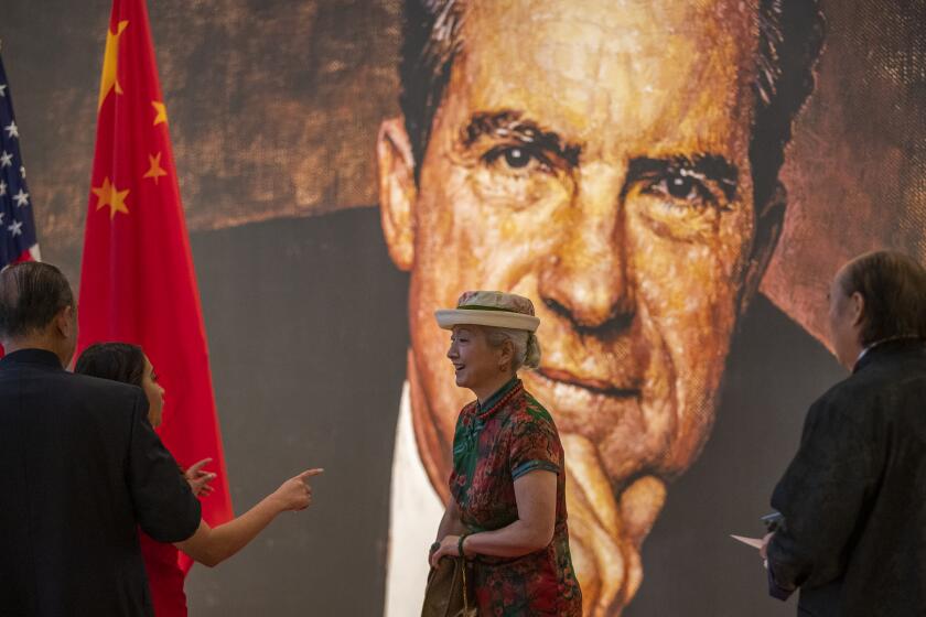 Yorba Linda, CA - February 24: Venus Xing, of Yorba Linda, waits to pose for a portrait in front of a Norman Rockwell portrait of former President Richard Nixon before Chinese ambassador Qin Gang spoke at The Richard Nixon Library & Museum to mark 50 years since Nixon visited China and began diplomatic relations. Photo taken at The Richard Nixon Library & Museum in Yorba Linda Thursday, Feb. 24, 2022. Dr. Henry Kissinger led the commemoration with virtual remarks. Speakers included the Honorable Elaine Chao, who served as the first Chinese-American member of a President's Cabinet, 24th U.S. Secretary of Labor and 18th U.S. Secretary of Transportation, former U.S. Ambassador to the PRC Stapleton Roy, and PRC Ambassador to the United States Qin Gang. This is the first visit to the U.S. West Coast by Ambassador Qin Gang. (Allen J. Schaben / Los Angeles Times)