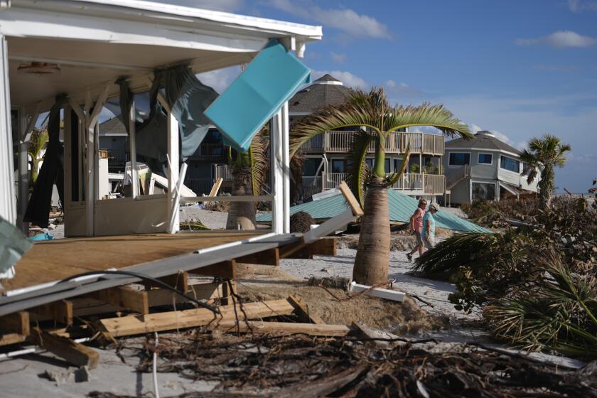 ARCHIVO - La residente Kerry Flyyn y una amiga caminan junto a una casa destrozada por el huracán Milton, en Englewood, Florida, el 13 de octubre de 2024. (AP Foto/Rebecca Blackwell, Archivo)