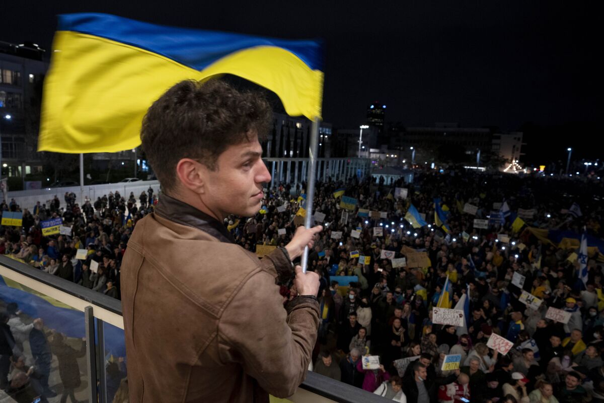 Un hombre ondea una representación de la bandera ucraniana frente a la Plaza Habima de Tel Aviv, 