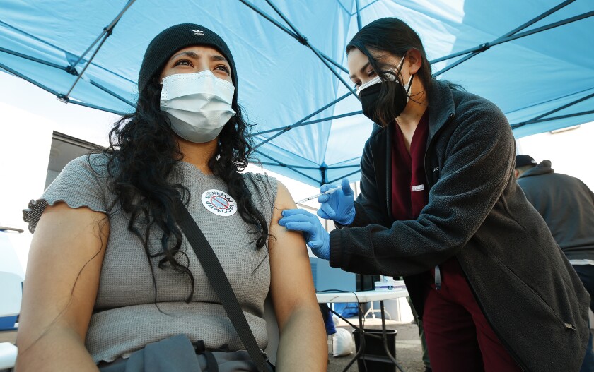 A woman gets vaccinated outdoors.