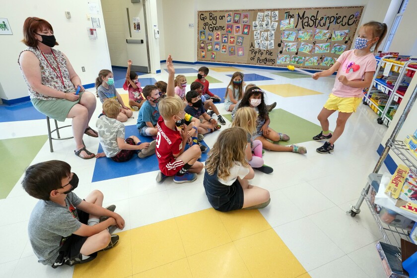 FILE — Kelly Sheridan, left, and her first grade students wear face masks as one of the students makes a presentation during class in a hallway at the Milton Elementary School, May 18, 2021, in Rye, N.Y. The New York State Education Department is telling schools to continue to require masks despite a judge’s ruling overturning the state's mask mandate. But some school districts already are rushing to drop the requirement. The Education Department said in a statement Tuesday, Jan. 25, 2022 that the state was appealing the ruling, which could temporarily halt it, and that schools should follow the mask rule in the meantime. (AP Photo/Mary Altaffer, File)