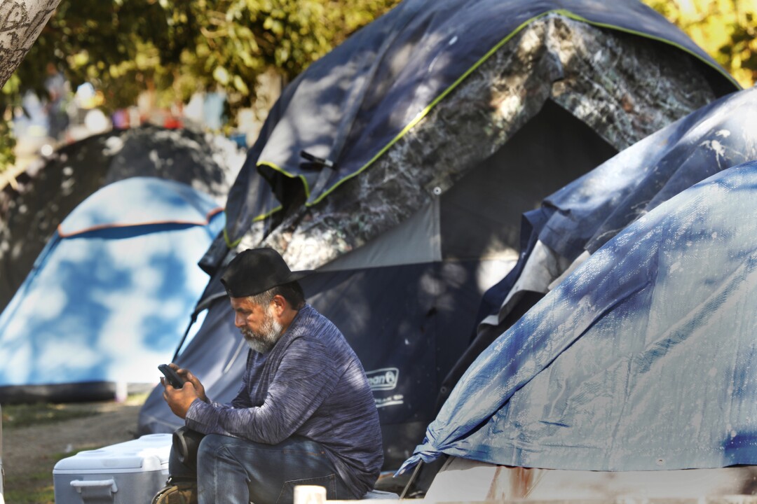 A man is resting outside a tent in MacArthur Park