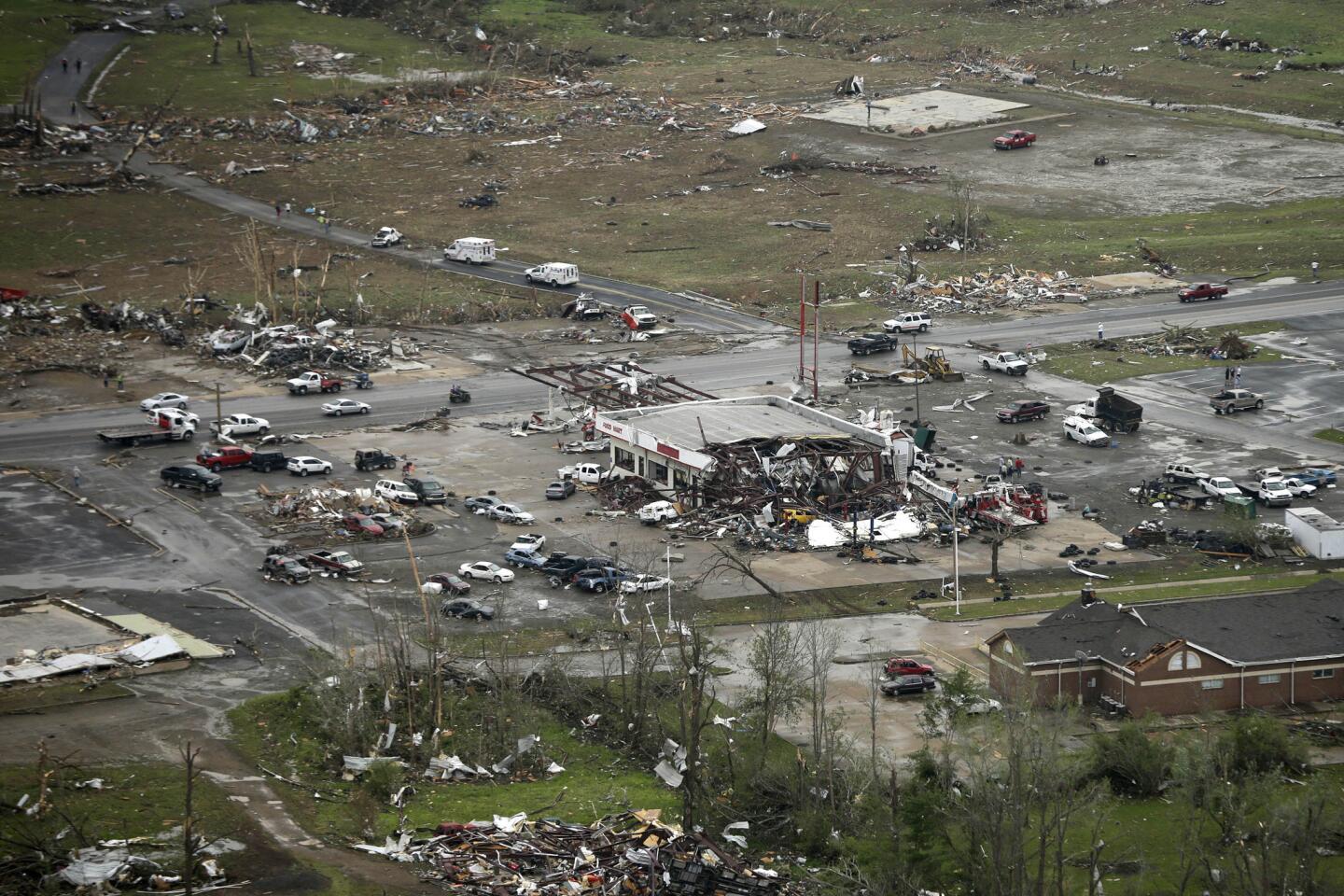 A storm-damaged convenience store, center, sits among rubble along U.S. Highway 64 in Vilonia, Ark.