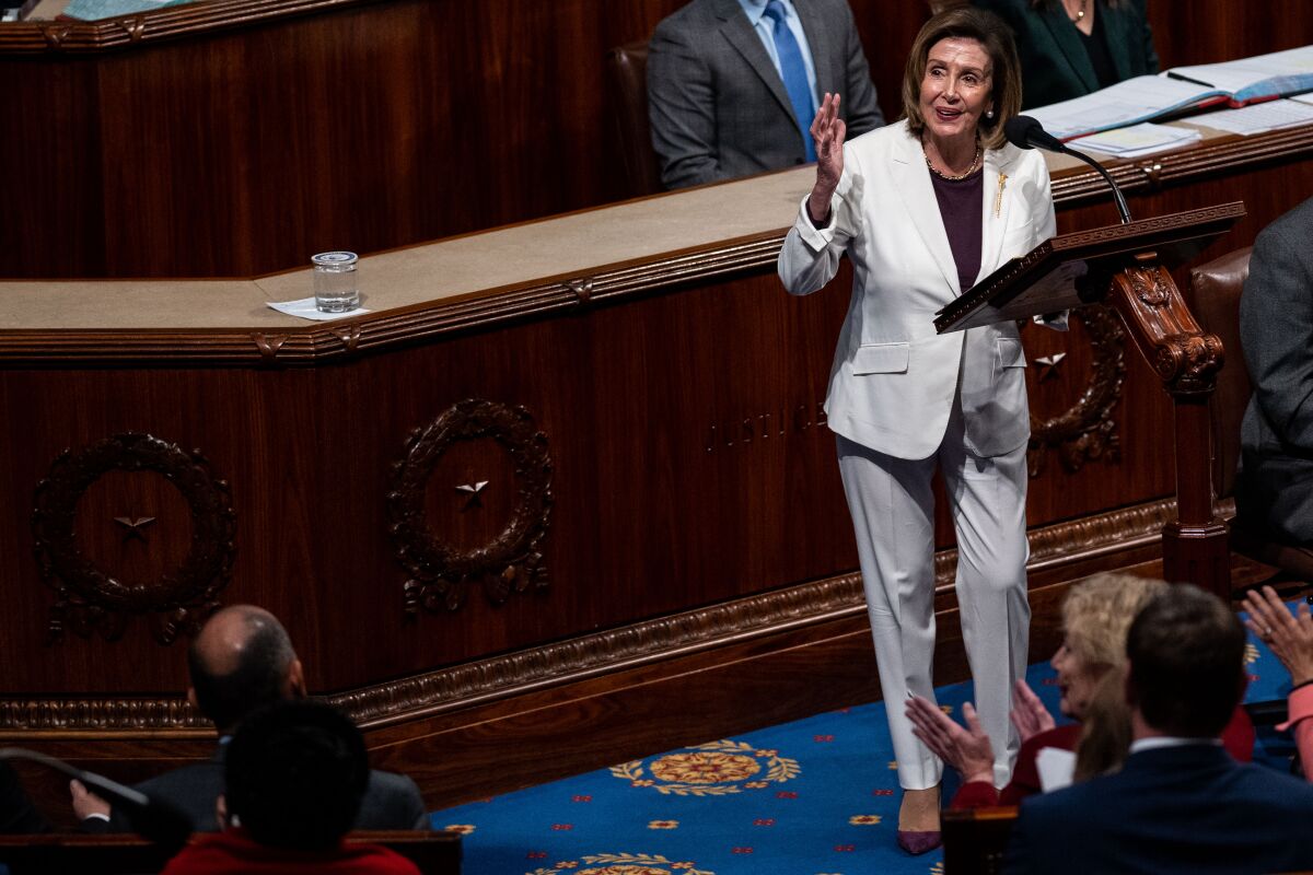 A woman in a white pants suit speaking at a lectern