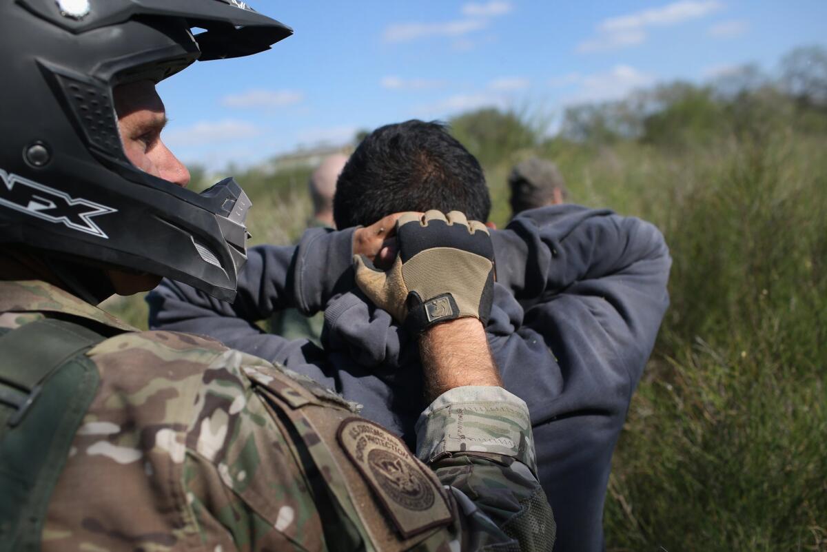 U.S. Border Patrol agent leads immigrants through the brush after capturing them this week near the Mexican border close to Rio Grande City, Texas.