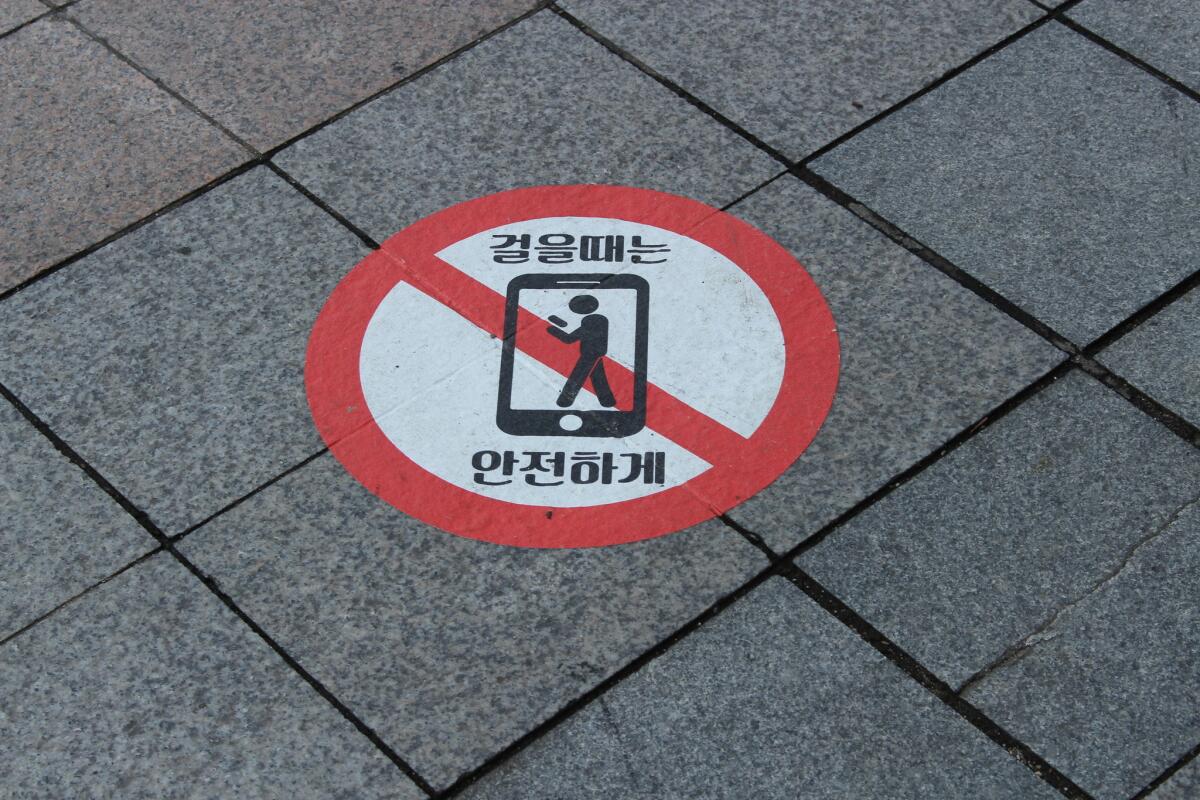 Pedestrians in Seoul are reminded to look where they are going. The Korean text translates as "Walk safely."