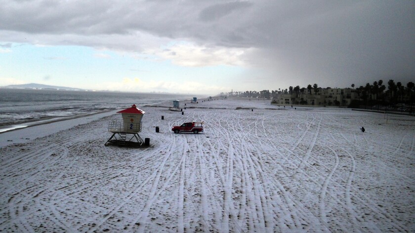 Hail covers the beach north of the Huntington Beach Pier on Monday morning.
