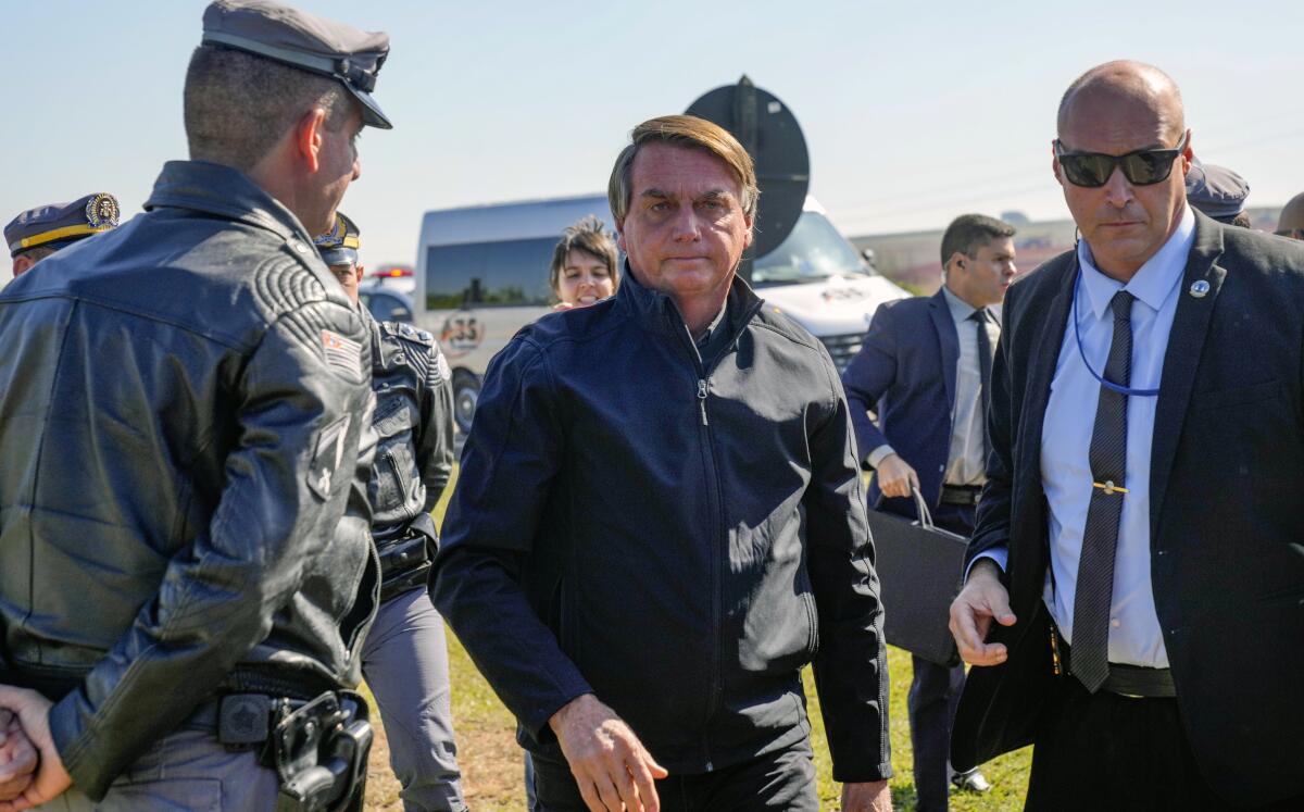 Brazilian President Jair Bolsonaro surrounded by aides arrives at a resort hotel