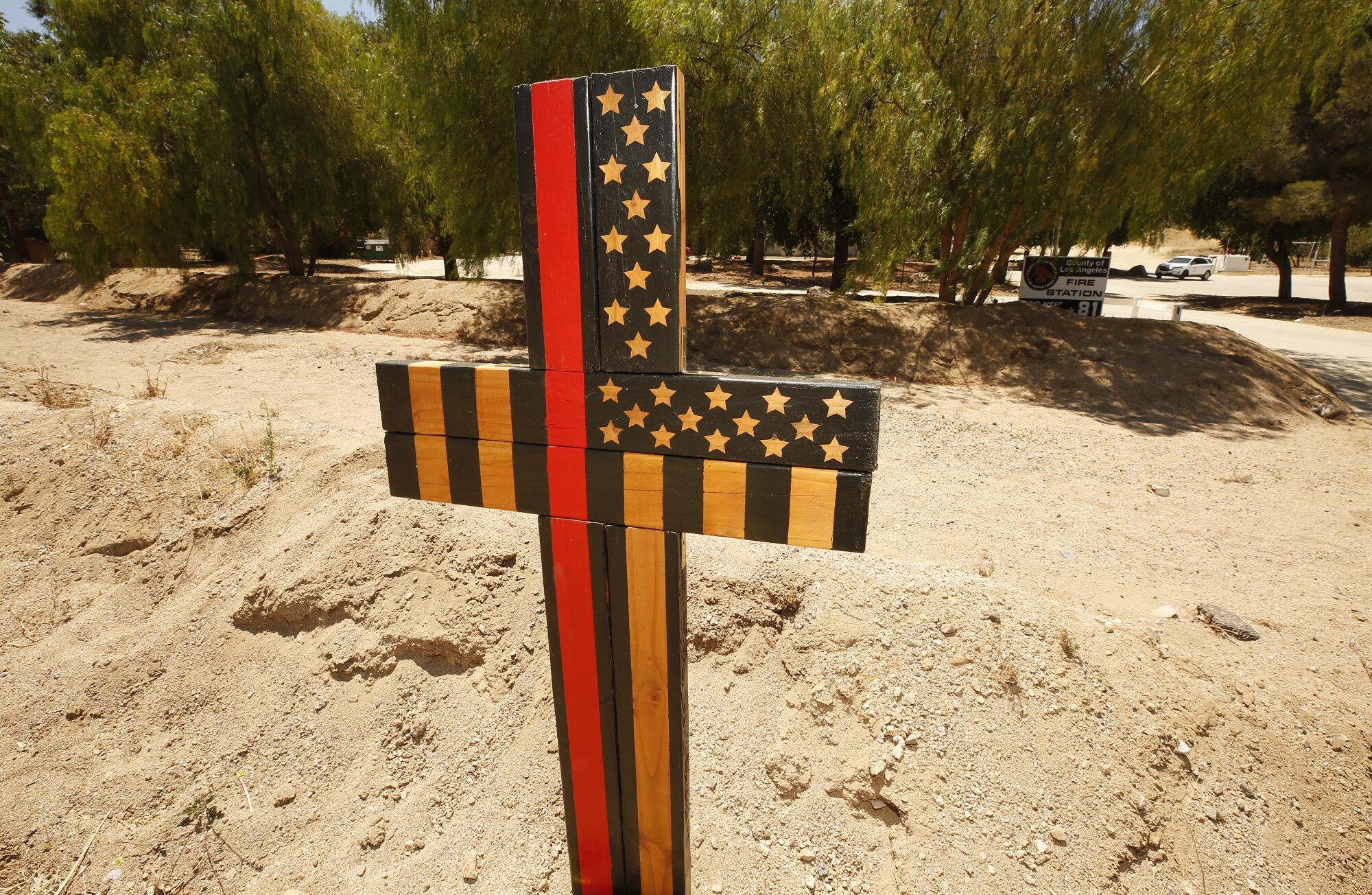A memorial cross with American flag symbols erected outside Fire Station 81 in Agua Dulce in June 2021