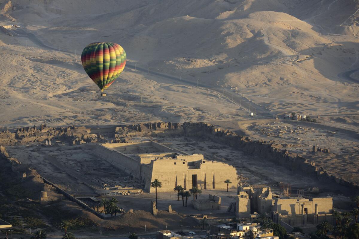 FILE -- A hot air balloon flies over the mortuary temple of Ramsis III at Medinet Habu on the west bank of the Nile River in Luxor, Egypt, April 1, 201. Egyptian authorities suspended hot air ballooning over the ancient city of Luxor after two tourists were lightly injured during a ride early on Monday, July 18, 2022. (AP Photo/Amr Nabil, File)
