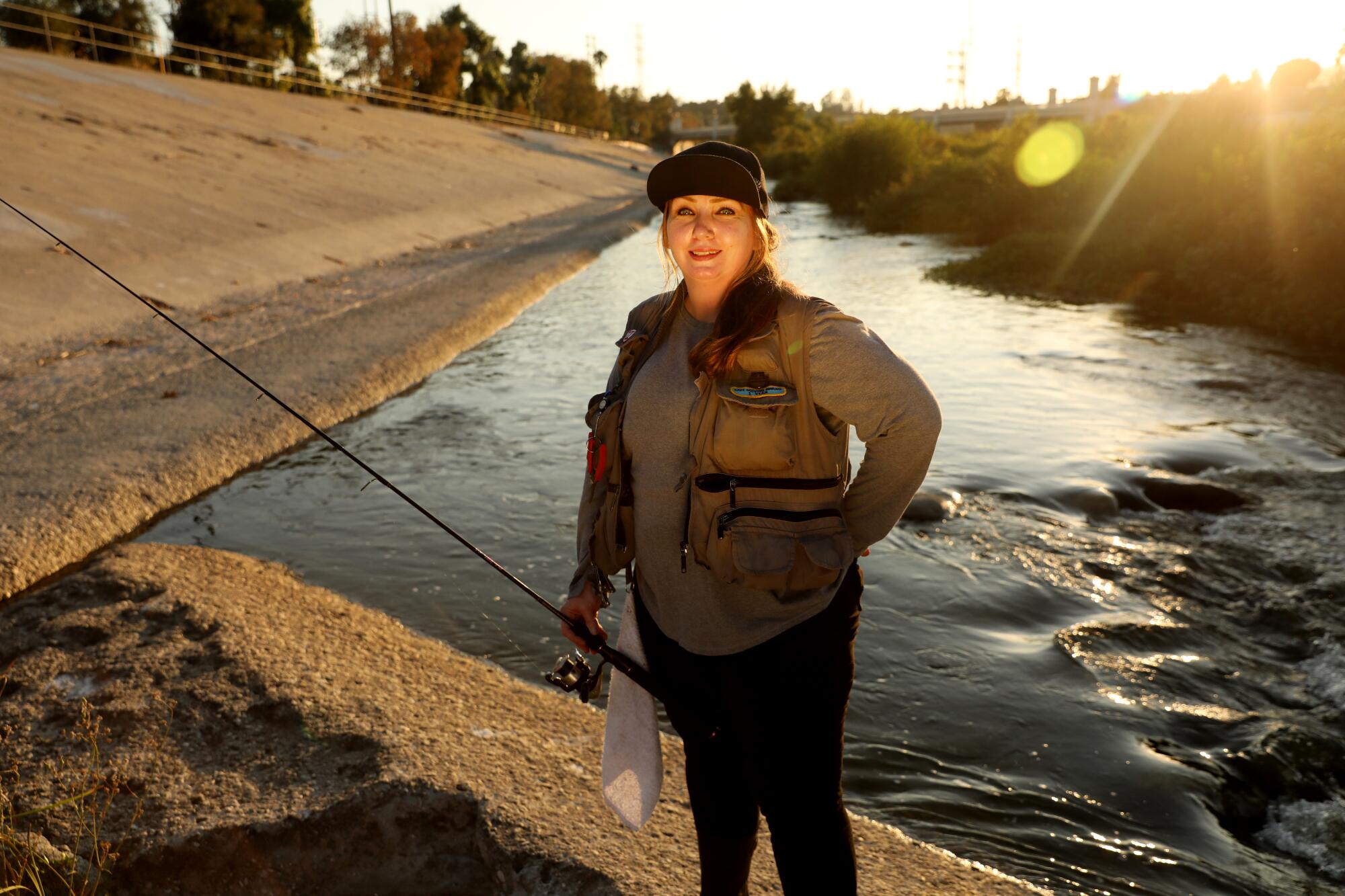 Maggie Harris stands near the river with her fishing pole. 