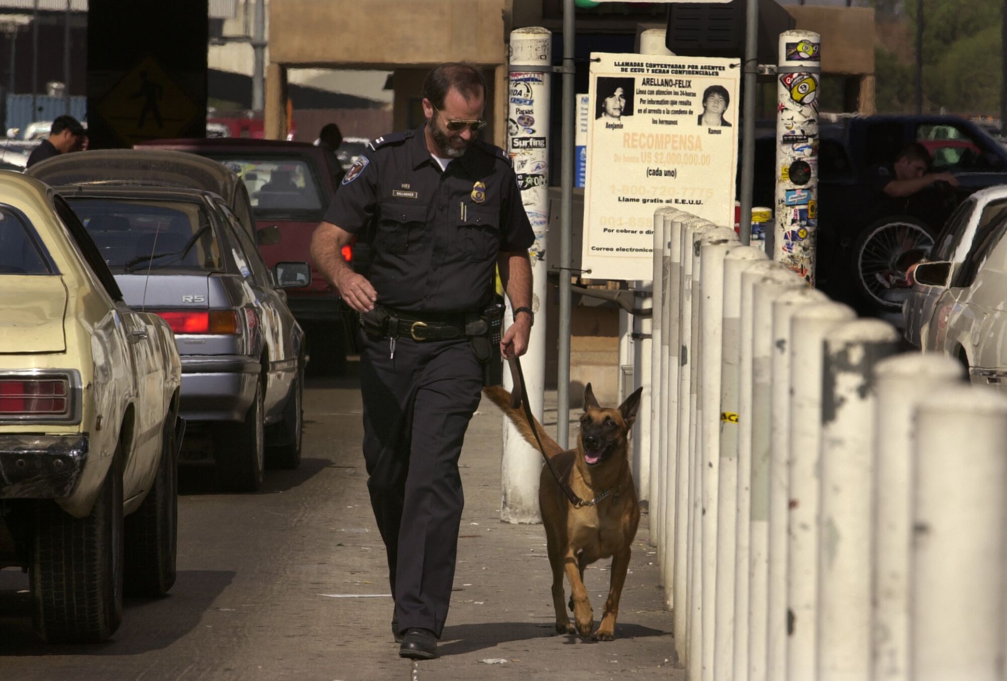 A U.S. Customs agent walks his dog along the lines of cars waiting to cross at the San Ysidro Port of Entry.