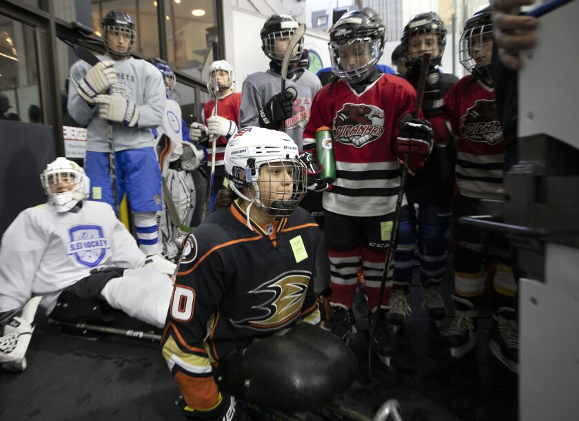 Lera Doederlein waits while a Zamboni cleans the ice before going out to sled hockey practice with her San Diego Ducks team.