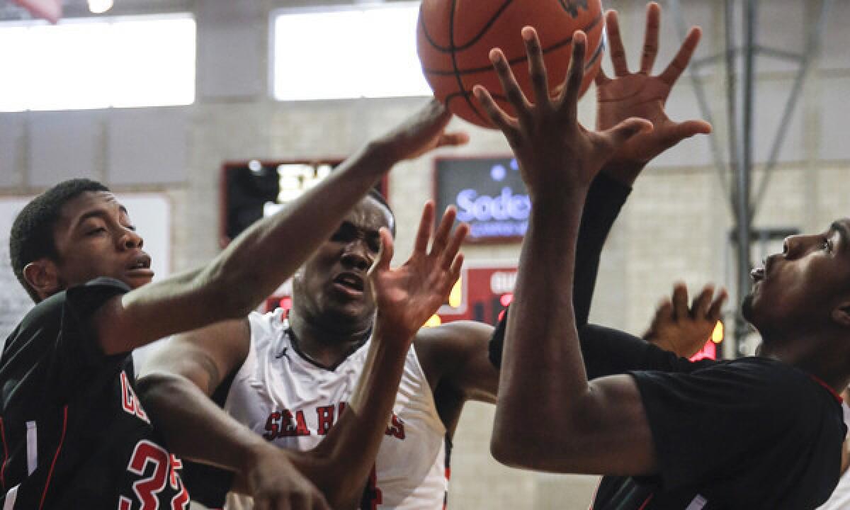 Redondo's Terrell Carter, center, battles Corona Centennial's Jalen Hill, left and Deontae North for a rebound during Centennial's 67-60 win in the Nike Extravaganza XIX at Mater Dei High School on Saturday.