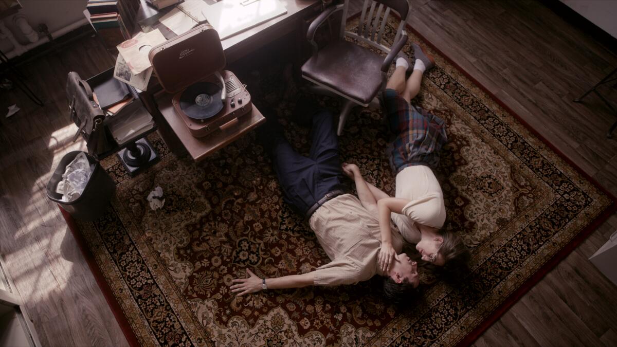 A man and a woman lay — and lie — on a rug together