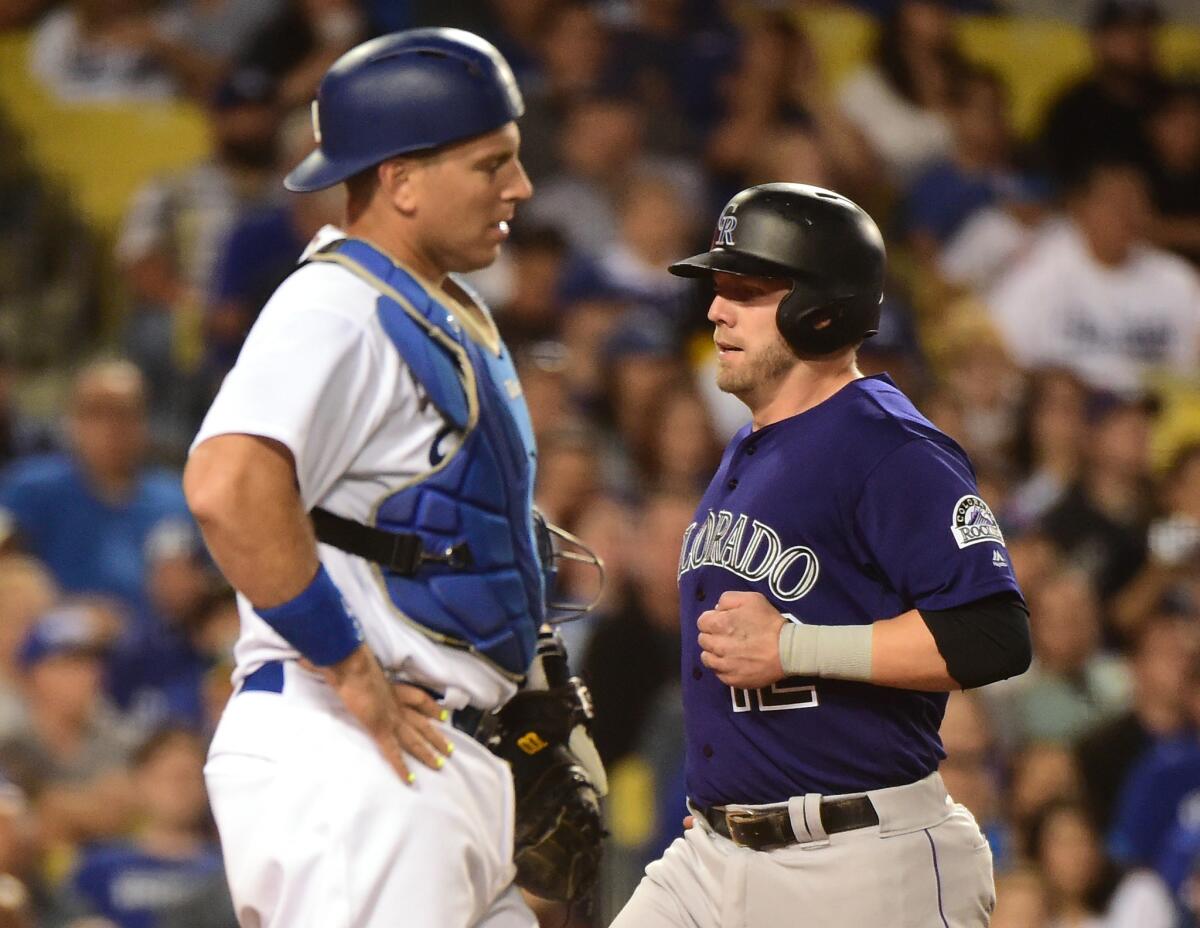 Rockies first baseman Mark Reynolds (12) scores a run in front of Dodgers catcher A.J. Ellis to take a 2-1 lead during the fifth inning.