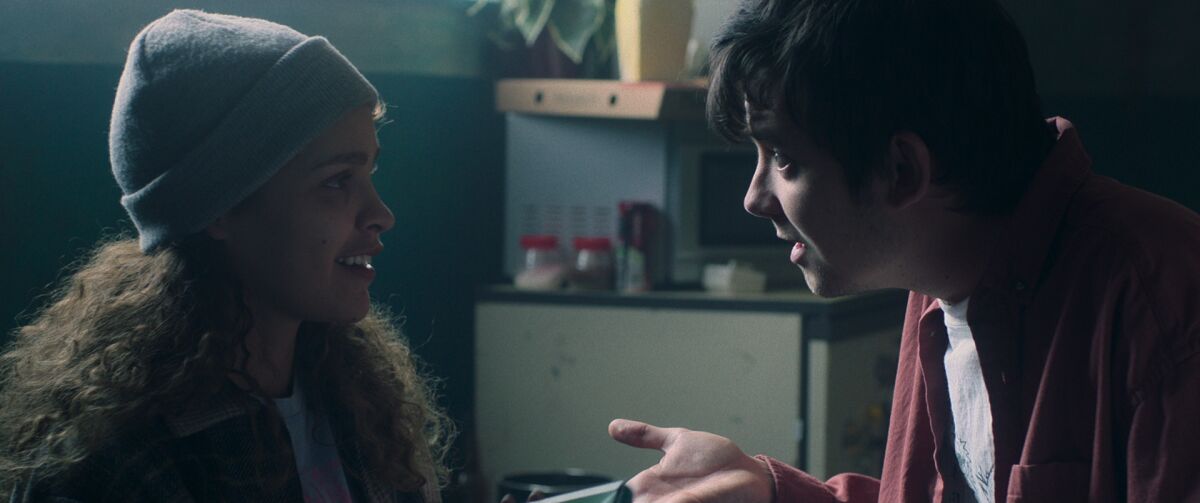 A young woman in a knit cap listens to a young man in the movie "Choose or Die."