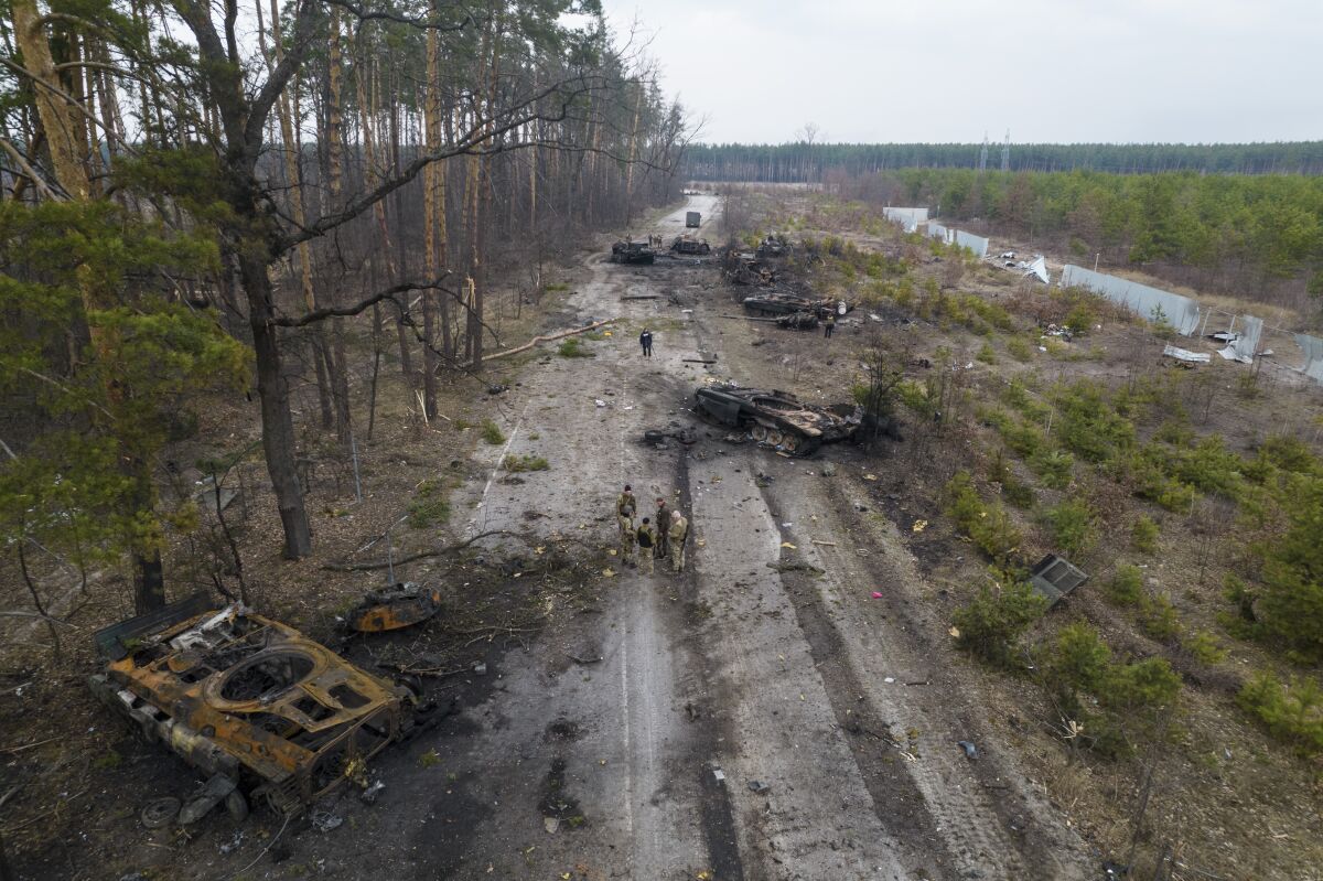 A muddy road is littered with Russian armored vehicles destroyed by Ukrainian fighters