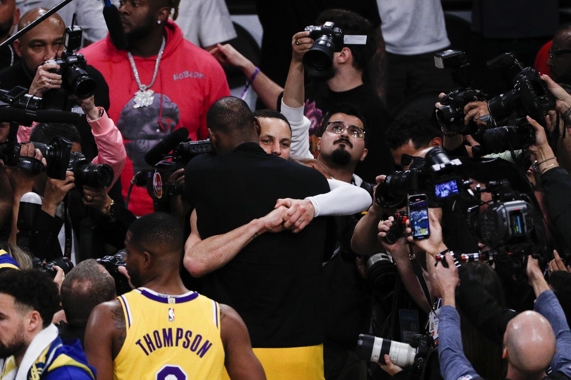Lakers forward LeBron James, front, hugs Golden State Warriors guard Stephen Curry.