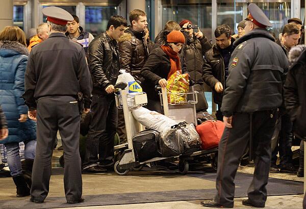 After the explosion, police officers watch passengers make their way through the airport, which remained open.