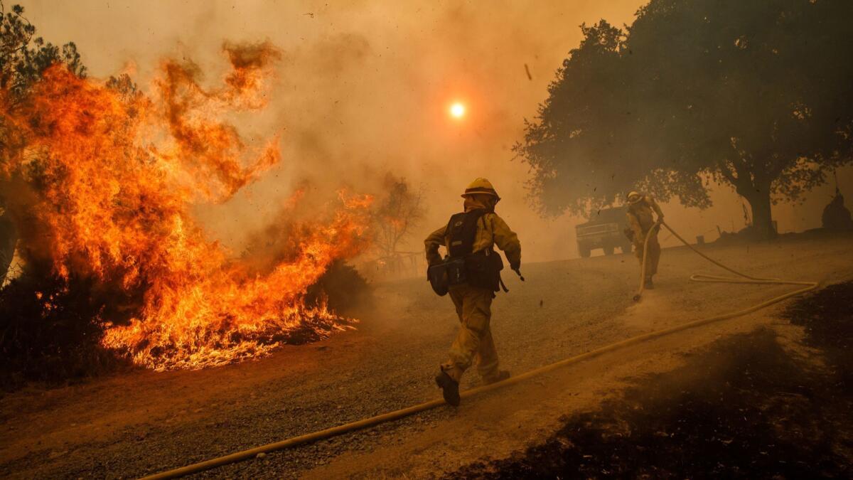Firefighters work to keep flames from the River fire from destroying a home near Lakeport, Calif., on July 31.