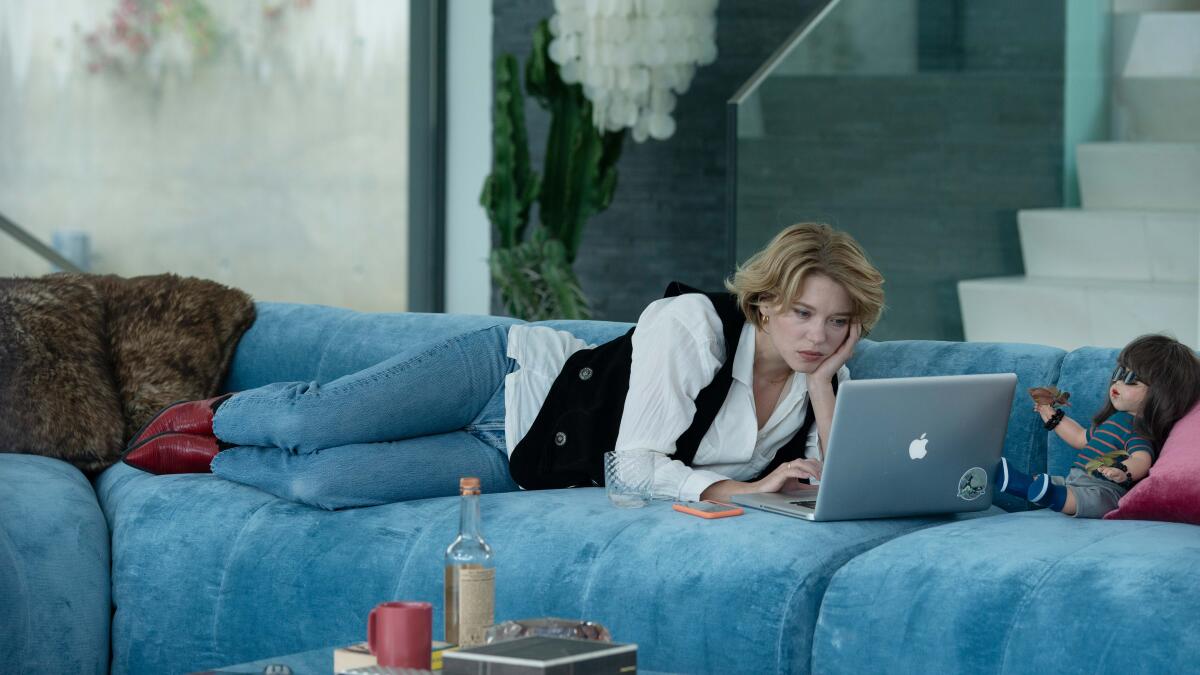 A woman looks at her laptop on a couch.
