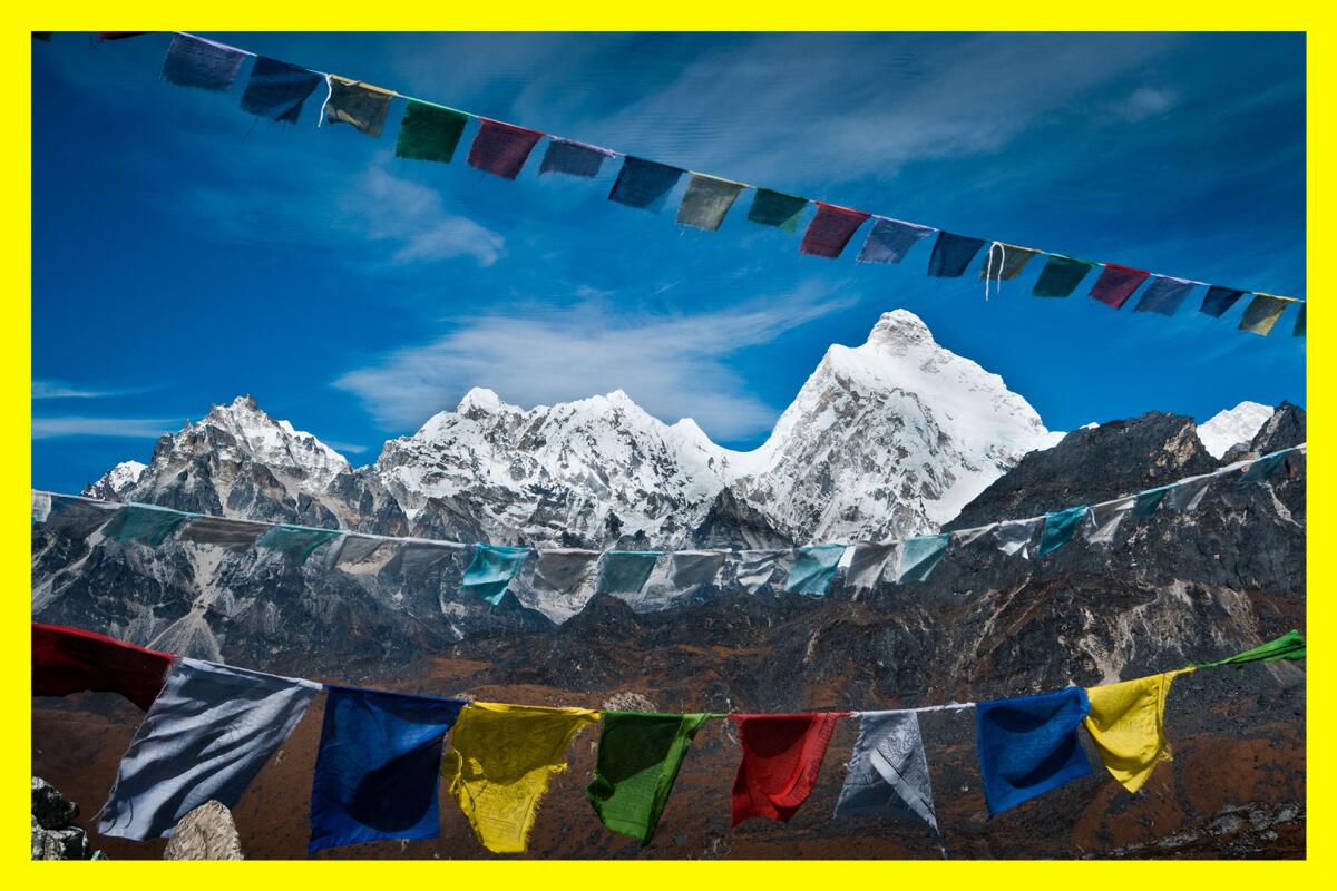 Colorful square cloth flags fluttering with a view of snowcapped mountains in the background