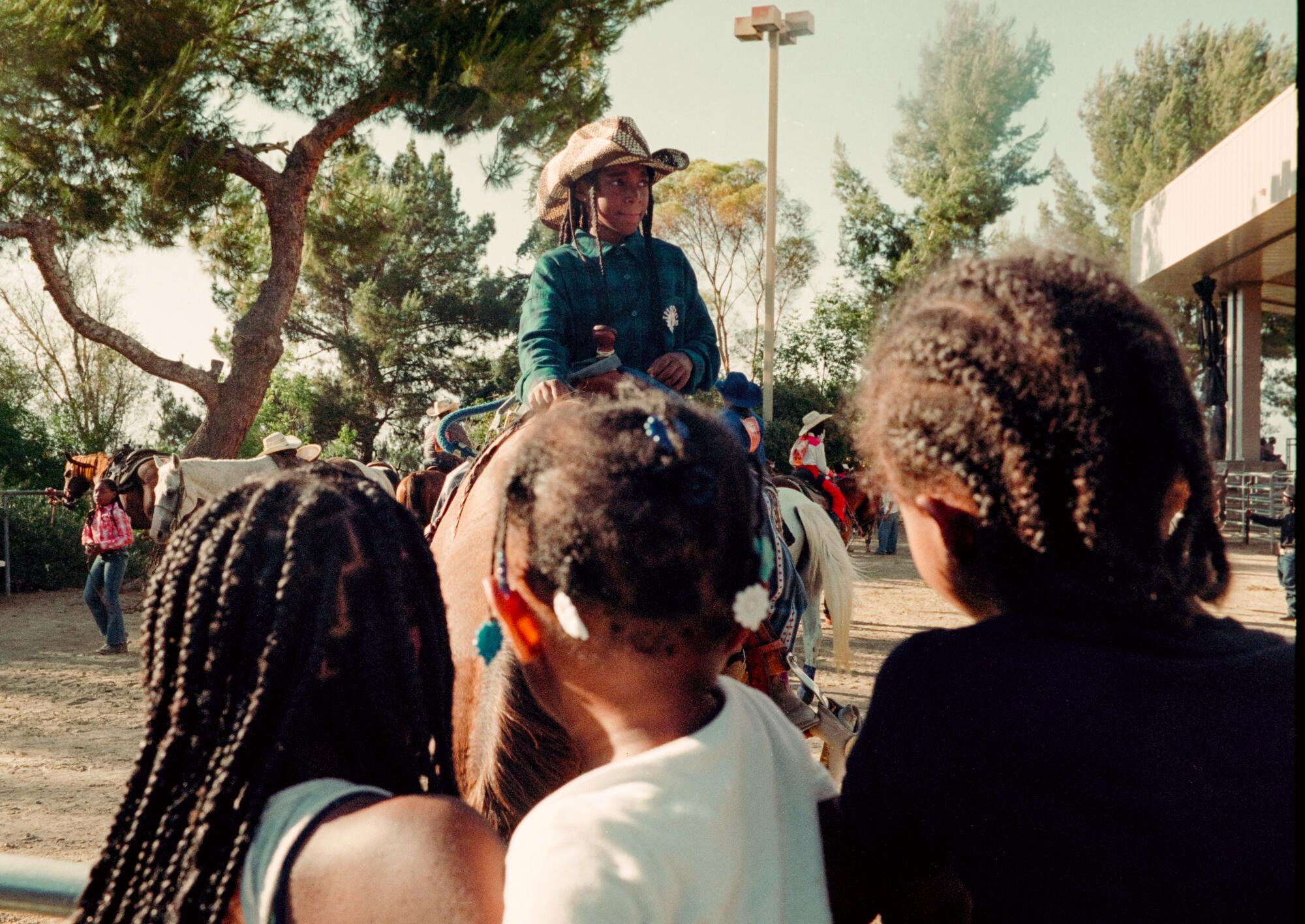 Boy on horseback as children watch at Bill Pickett Rodeo