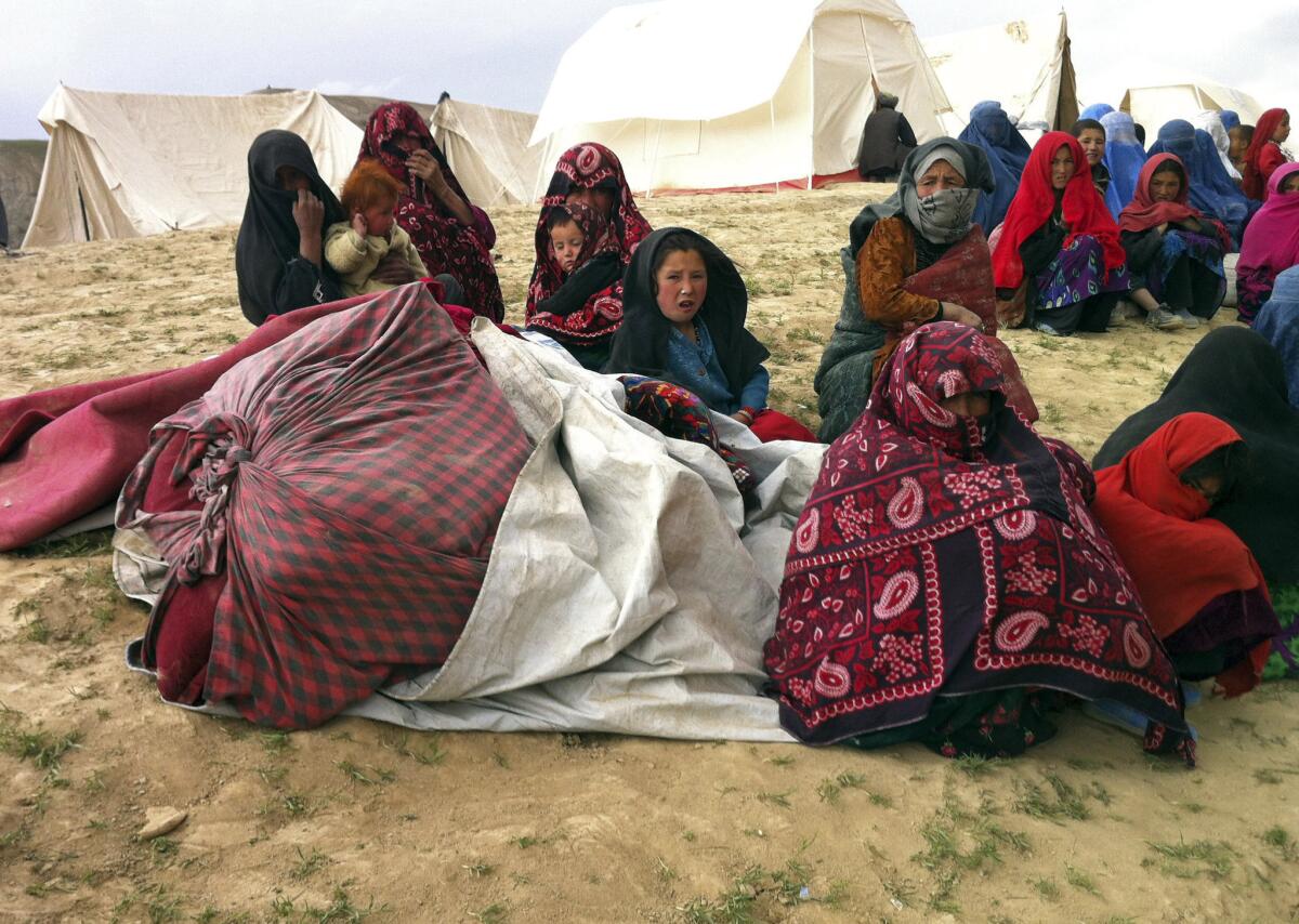 Survivors sit with their possessions near the site of Friday's landslide that buried their village in northeastern Afghanistan.
