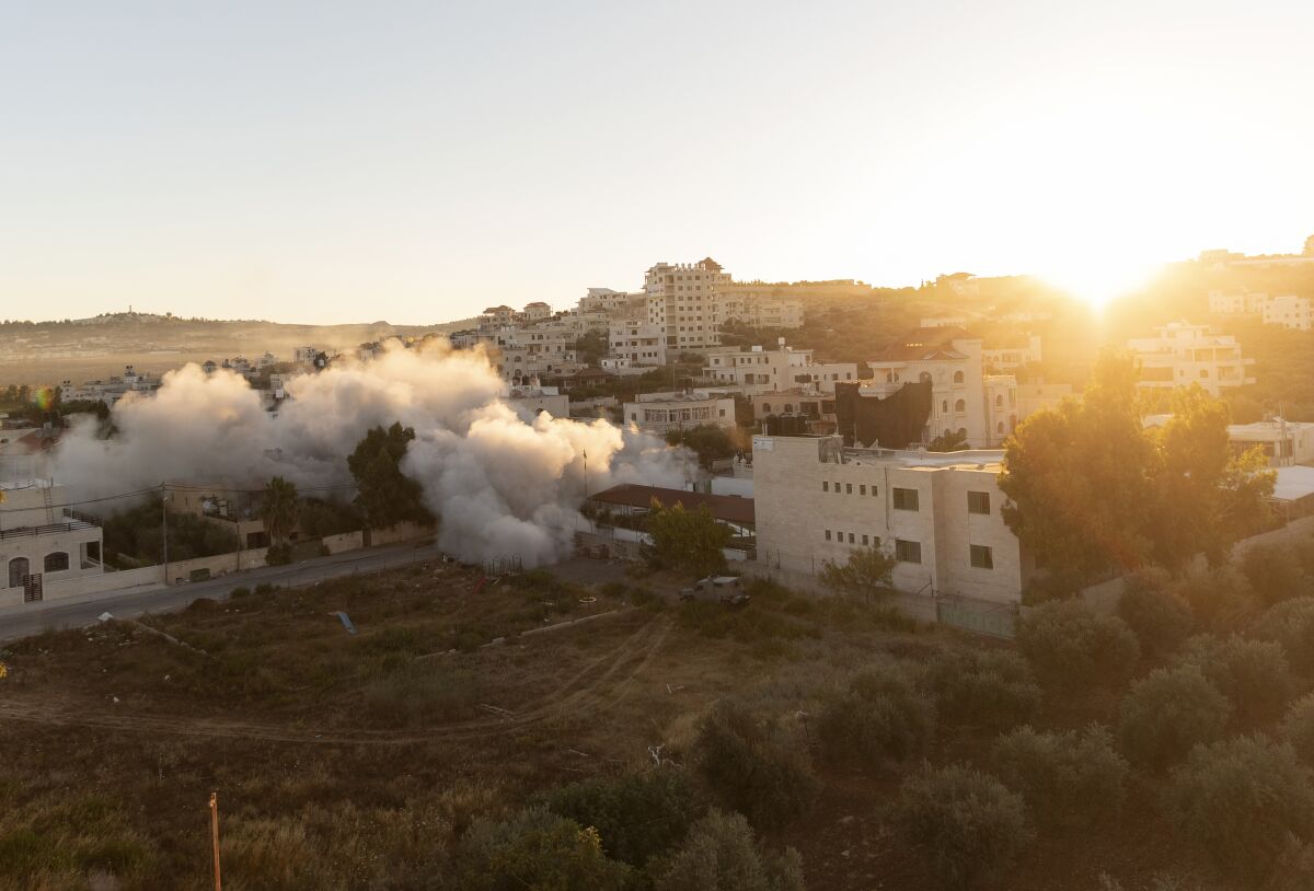 The sun rises while an Israeli army unit demolishes the house of Palestinian American Muntasser Shalaby using controlled explosions, in the West Bank village of Turmus Ayya, north of Ramallah, Thursday, July. 8, 2021. Israeli forces on Thursday demolished the family home of Shalaby who is accused of being involved in a deadly attack on Israelis in the West Bank in May. (AP Photo/Nasser Nasser)