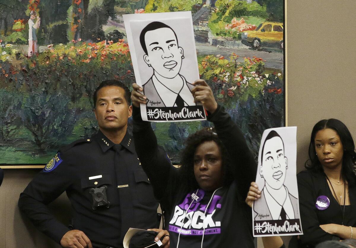 Protesters hold up signs honoring Stephon Clark as then-Police Chief Hahn stands by
