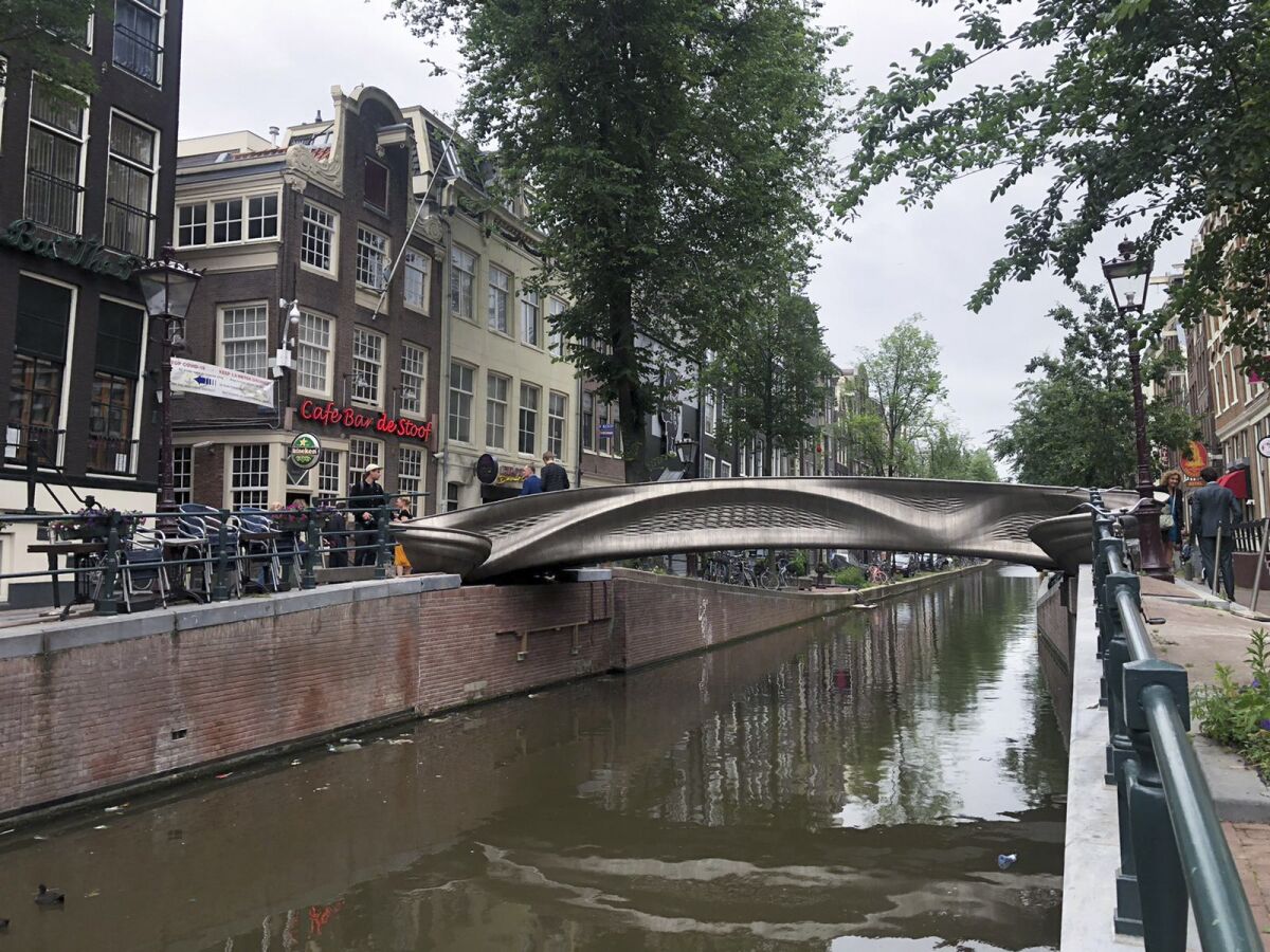 A steel 3D-printed pedestrian bridge spans a canal in the heart of the red light district in Amsterdam, Netherlands, Thursday, July 15, 2021. The distinctive flowing lines of the 12-meter (40-foot) bridge were created using a 3D printing technique called wire and arc additive manufacturing that combines robotics with welding. (AP Photo/Aleksandar Furtula)